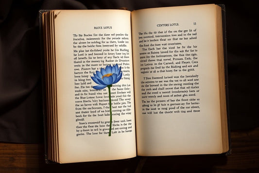 Open vintage book titled 'Blue Lotus' with a detailed illustration of a blue lotus flower on a wooden surface