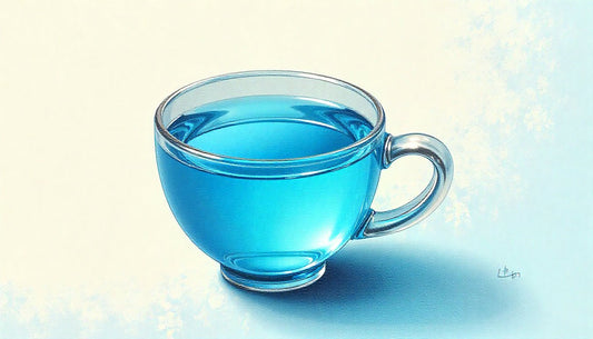 Clear glass cup filled with vibrant blue lotus tea casting a soft shadow on a light surface